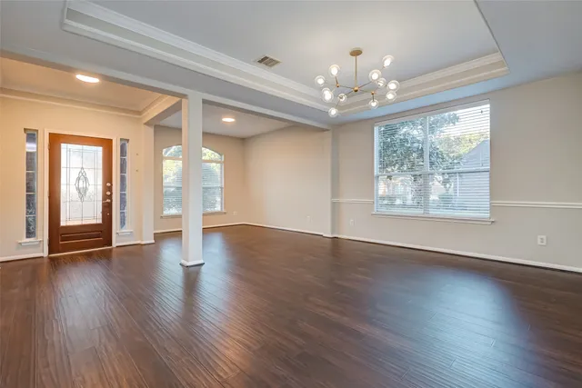 a view of an empty room with wooden floor and a window
