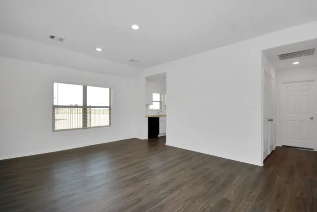 an empty room with wooden floor cabinet and windows