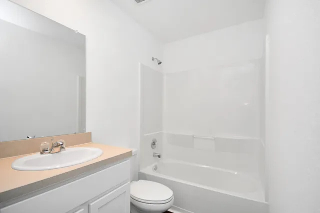 a bathroom with a bathtub shower sink vanity mirror and toilet