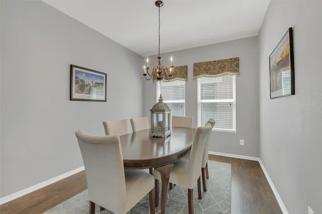 a dining room with furniture wooden floor a potted plant and a chandelier