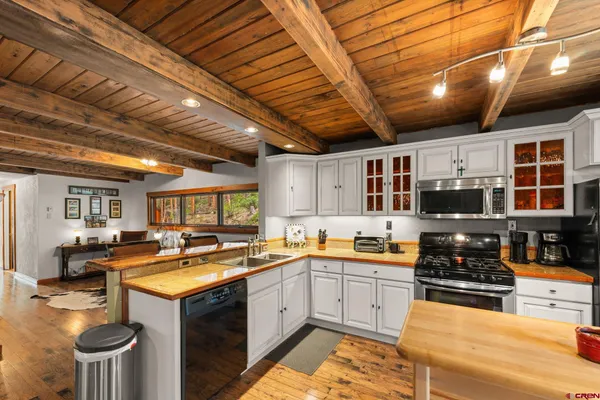 a large kitchen with lots of counter top space a sink and stainless steel appliances