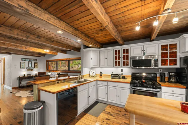 a large kitchen with lots of counter top space a sink and stainless steel appliances