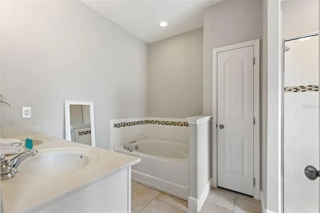 a bathroom with a sink vanity granite tub shower and a mirror