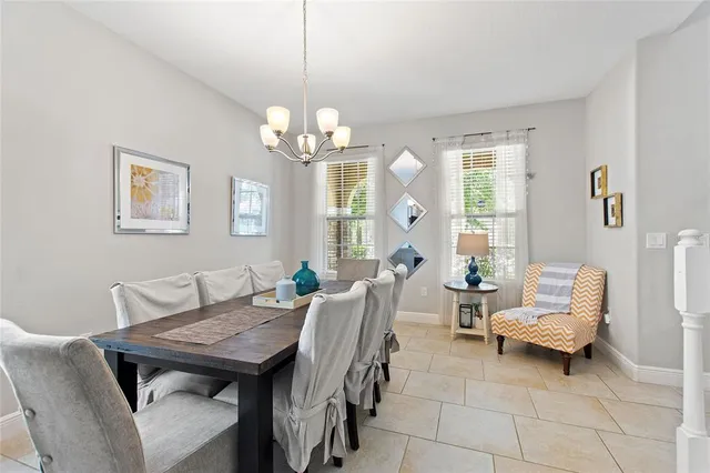 a kitchen with stainless steel appliances granite countertop a stove top oven a sink a dining table and chairs with white cabinets