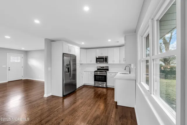 a kitchen with stainless steel appliances granite countertop a refrigerator stove top oven and cabinets with wooden floor