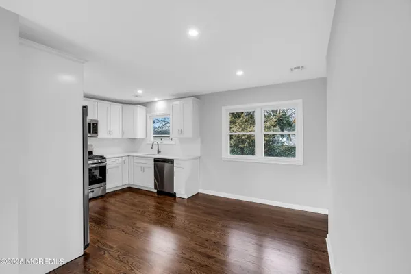 a view of a kitchen with a refrigerator wooden floor and a window