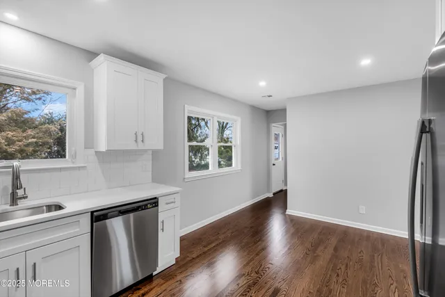 a view of a kitchen with a refrigerator wooden floor and a window