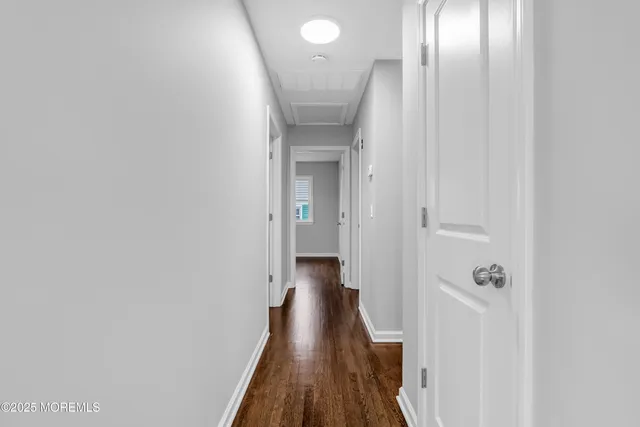 a view of a hallway with wooden floor and a bathroom