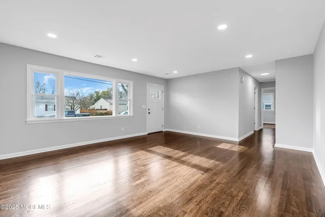 a view of an empty room with wooden floor and window