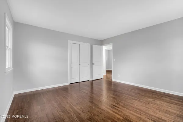 a view of an empty room with wooden floor and window