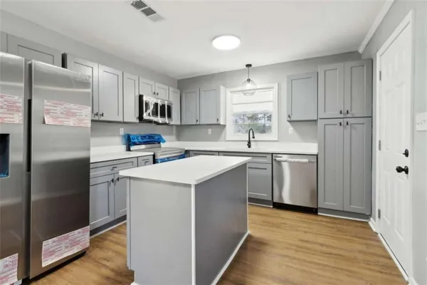 a kitchen with a sink a refrigerator a counter top space and cabinets