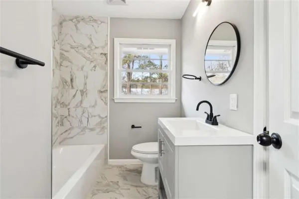 a bathroom with a granite countertop sink a toilet and a bathtub