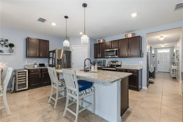 a kitchen with stainless steel appliances granite countertop a stove a sink a refrigerator a kitchen island with a dining table and chairs