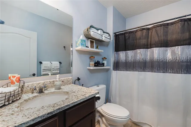 a bathroom with a granite countertop sink a toilet and shower