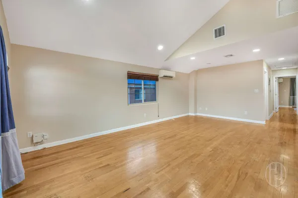 a view of an empty room with wooden floor and windows