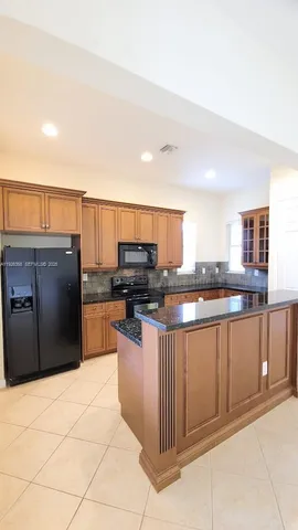 a kitchen with stainless steel appliances kitchen island granite countertop a refrigerator and cabinets