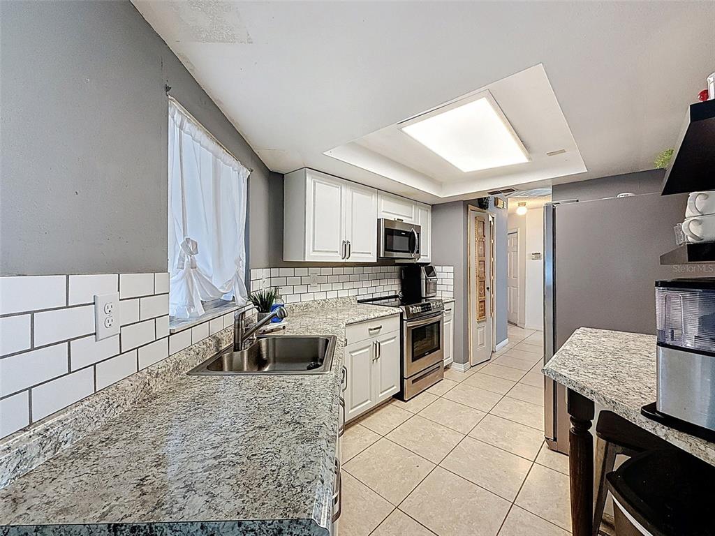 Undisclosed Address Spring Hill, FL 34608 - Photo 11 of 54 a kitchen with granite countertop a sink cabinets stainless steel appliances and a counter top space