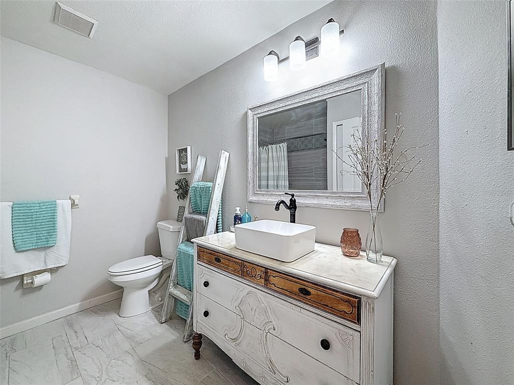 Undisclosed Address Spring Hill, FL 34608 - Photo 17 of 54 a bathroom with a toilet sink and mirror