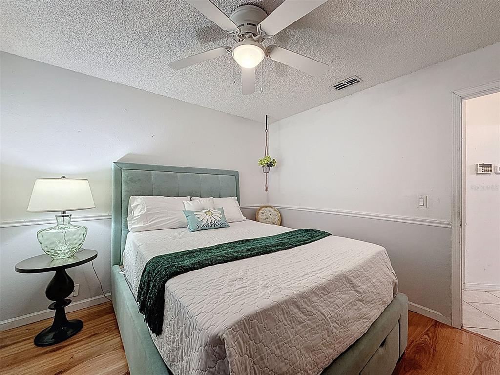 Undisclosed Address Spring Hill, FL 34608 - Photo 23 of 54 a bedroom with a bed and a lamp on table