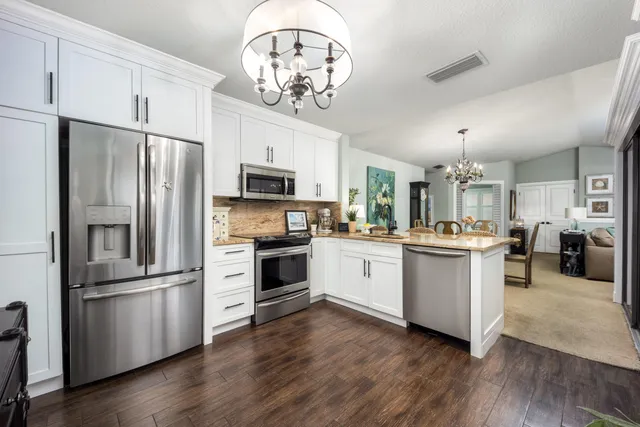 a kitchen with cabinets stainless steel appliances and wooden floor