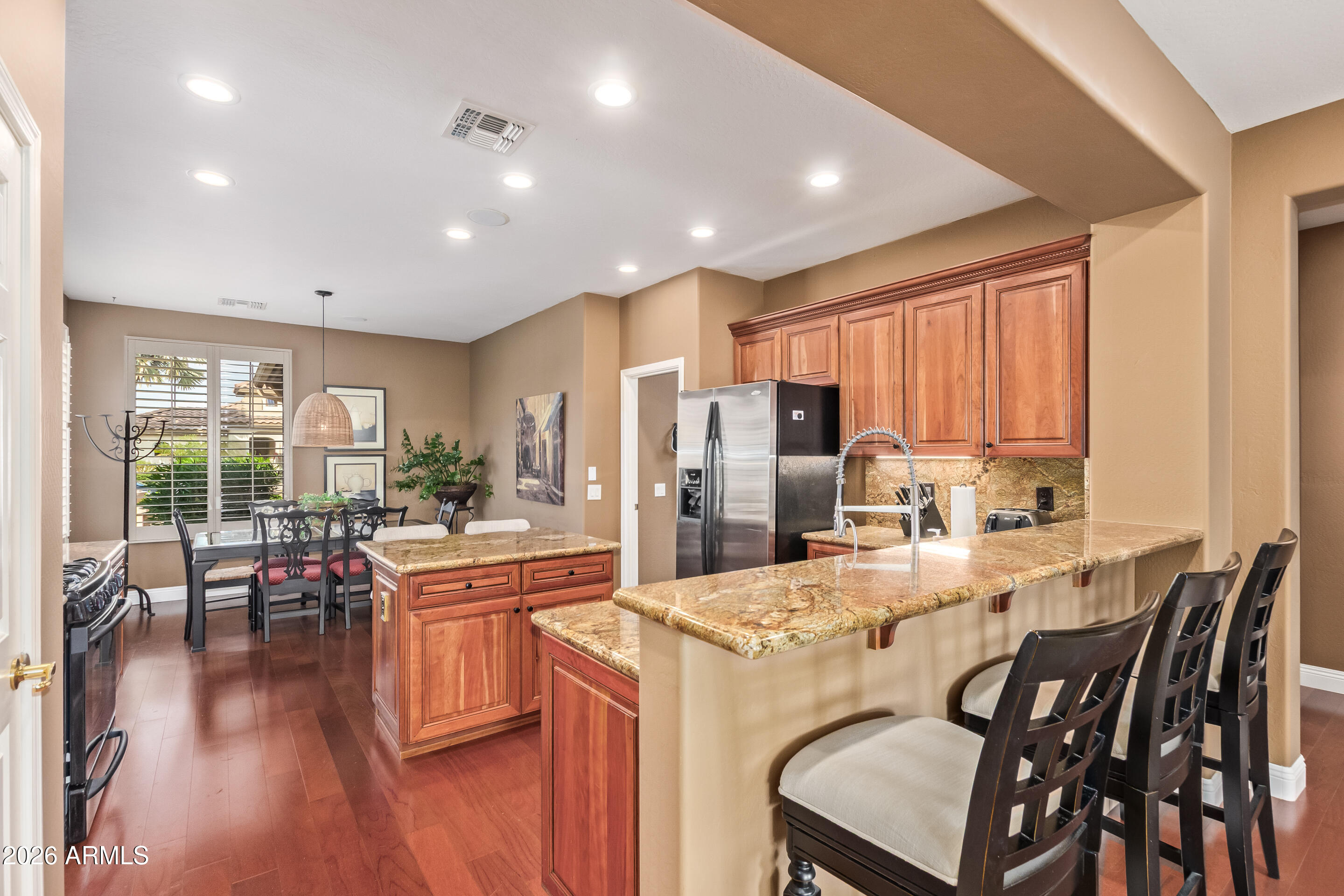 16287 West Cheery Lynn Road Goodyear, AZ 85395 - Photo 13 of 44 a kitchen with stainless steel appliances kitchen island granite countertop a dining table chairs refrigerator and sink