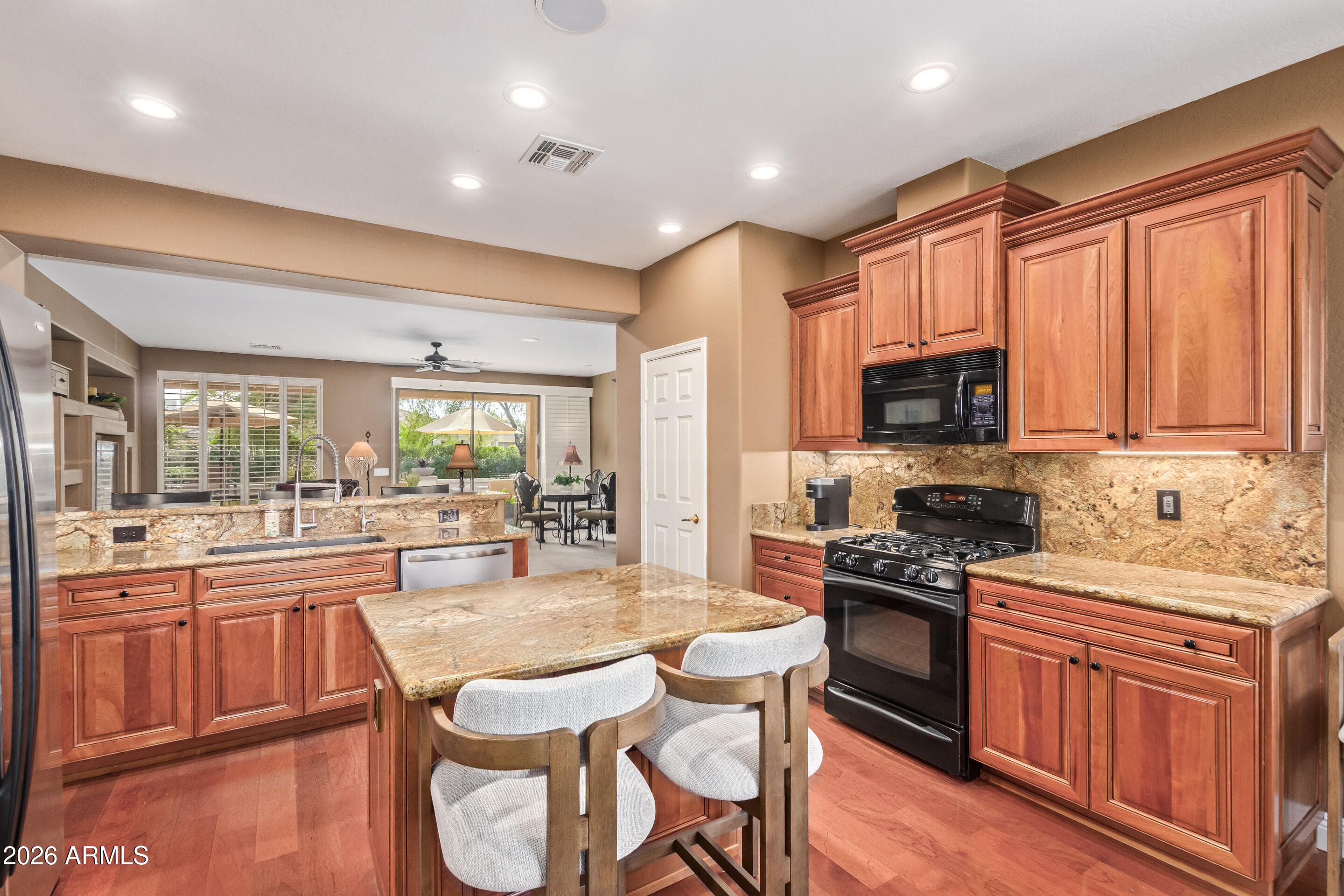 16287 West Cheery Lynn Road Goodyear, AZ 85395 - Photo 14 of 44 a kitchen with stainless steel appliances granite countertop a stove a sink dishwasher a dining table and chairs with wooden floor