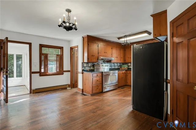 a kitchen with granite countertop stainless steel appliances a refrigerator cabinets and wooden floor
