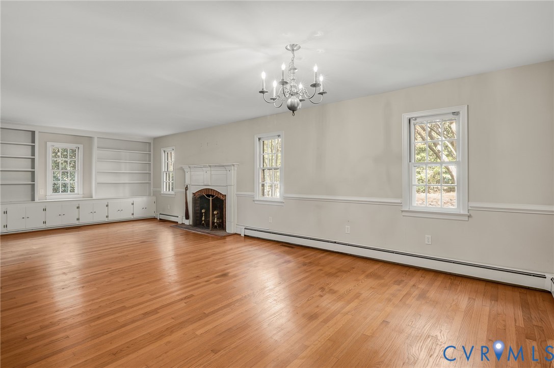 323 Church Street Wakefield, VA 23888 - Photo 9 of 50 an empty room with wooden floor chandelier and windows