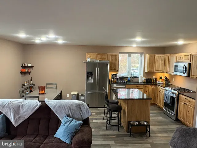 a kitchen with stainless steel appliances granite countertop a refrigerator a stove top oven and a dining table with wooden floor