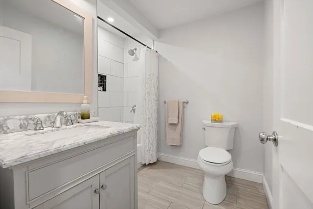 a bathroom with a toilet a sink a shower and a mirror