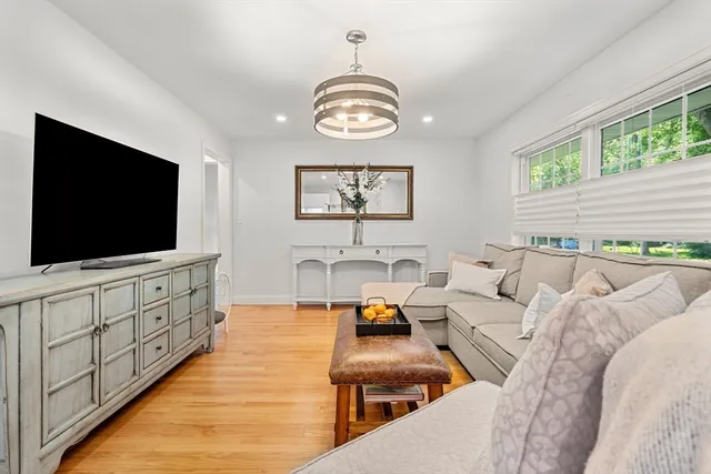 a living room with stainless steel appliances furniture a desk and chair with wooden floor