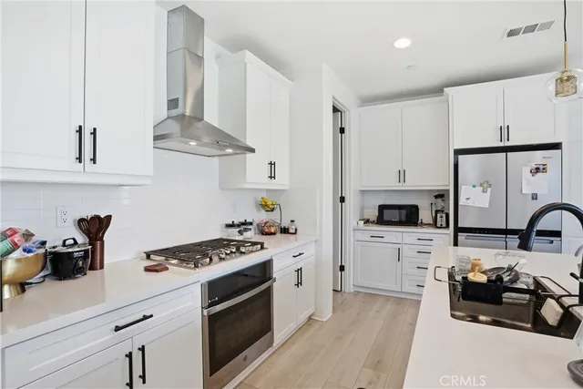 a kitchen with stainless steel appliances kitchen island granite countertop a sink a stove and a flat screen tv