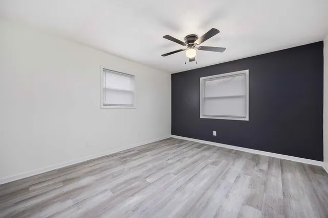 a view of an empty room with a window and wooden floor
