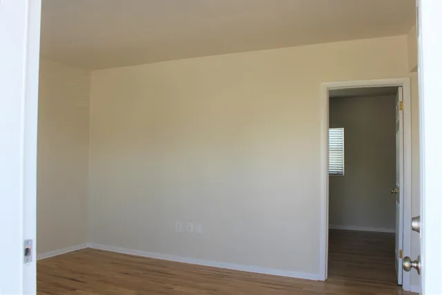 a view of an empty room and wooden floor and a window