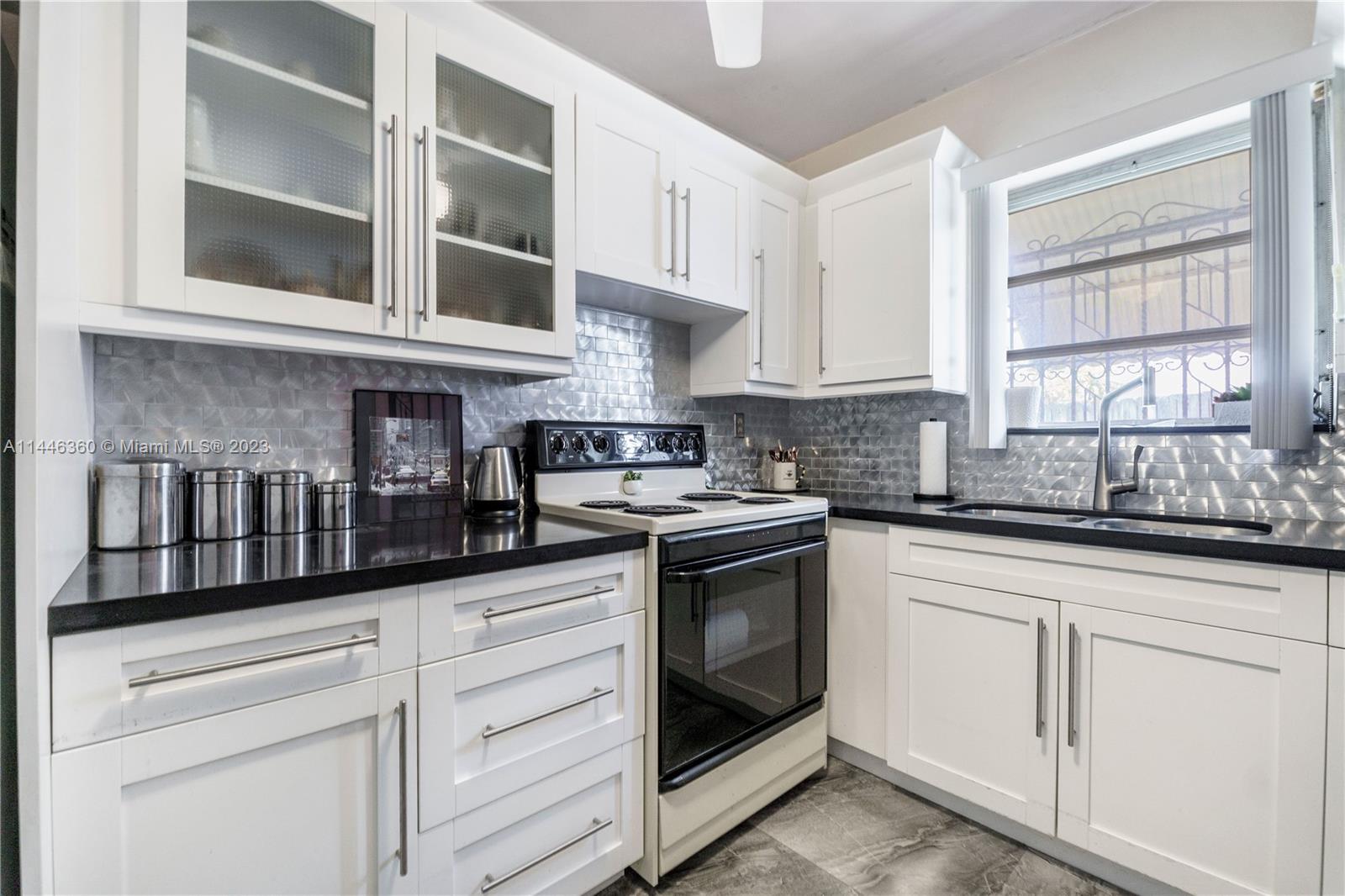 2446 Southwest 15th Street Miami, FL 33145 - Photo 15 of 42 a kitchen with stainless steel appliances granite countertop white cabinets and window