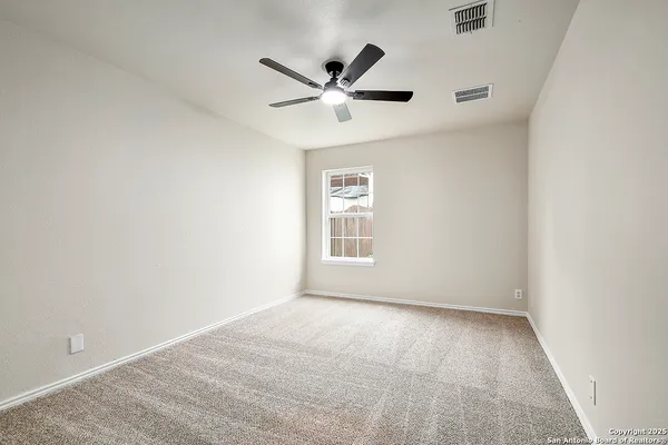 an empty room with ceiling fan and windows