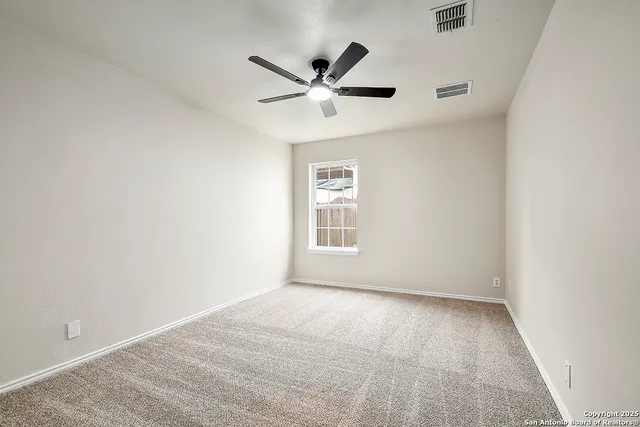 an empty room with ceiling fan and windows