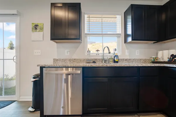 a kitchen with stainless steel appliances kitchen island granite countertop a refrigerator a sink dishwasher a stove and a dining table with wooden floor