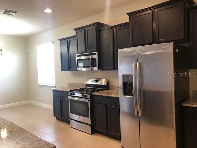 a kitchen with stainless steel appliances wooden cabinets a refrigerator and a stove