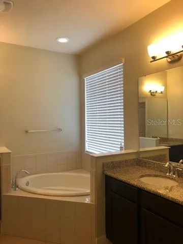 a bathroom with a granite countertop sink and a bathtub