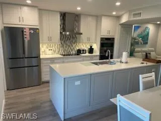 a kitchen with stainless steel appliances granite countertop a refrigerator a sink a stove and a wooden floors