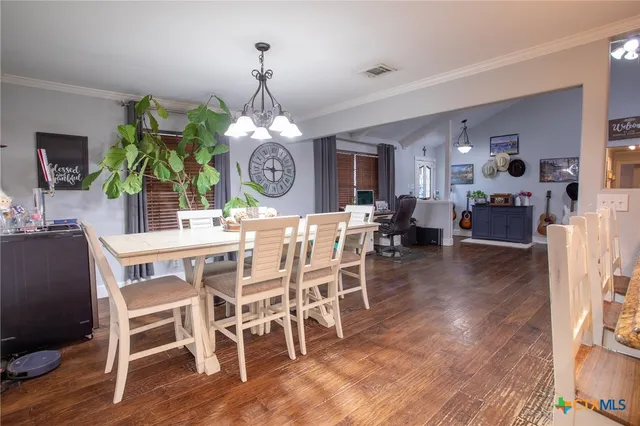 a view of a dining room and livingroom with furniture wooden floor a rug a painting and a chandelier