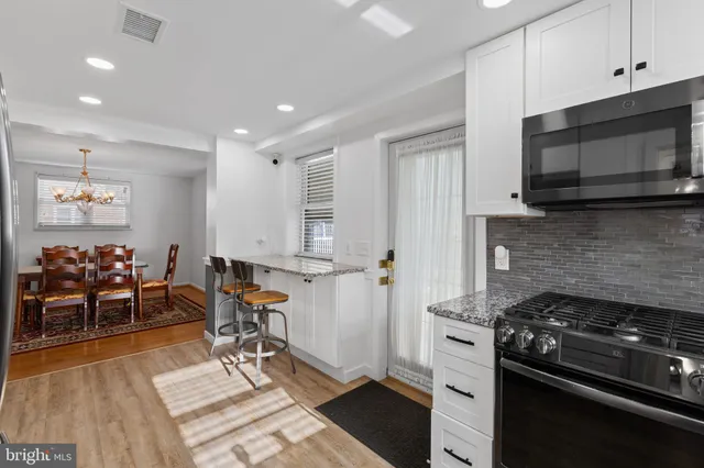 a kitchen with stainless steel appliances kitchen island granite countertop a stove and a wooden floors