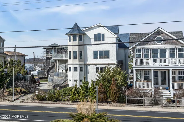 a front view of a building with a yard and potted plants