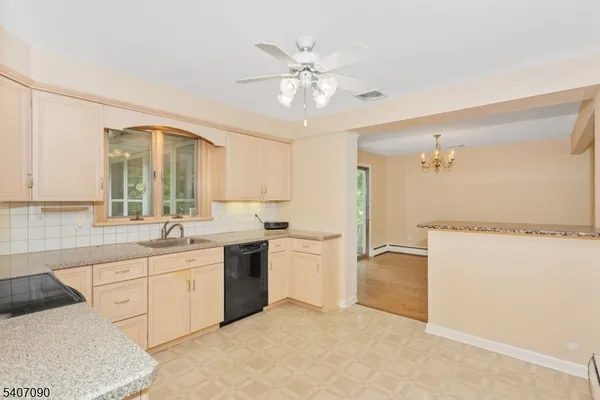 a view of a kitchen with a sink and dishwasher a refrigerator with white cabinets