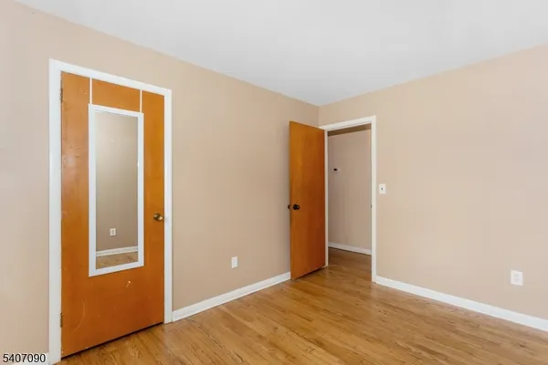 a view of an empty room with wooden floor and closet