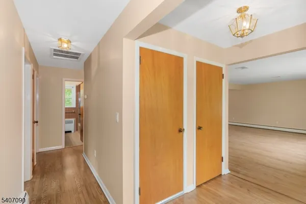 a view of a hallway with wooden floor and a bathroom