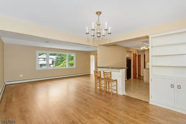 an empty room with wooden floor chandelier and windows