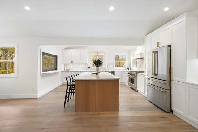 a kitchen with stainless steel appliances a refrigerator a stove a sink dishwasher and a dining table with wooden floor