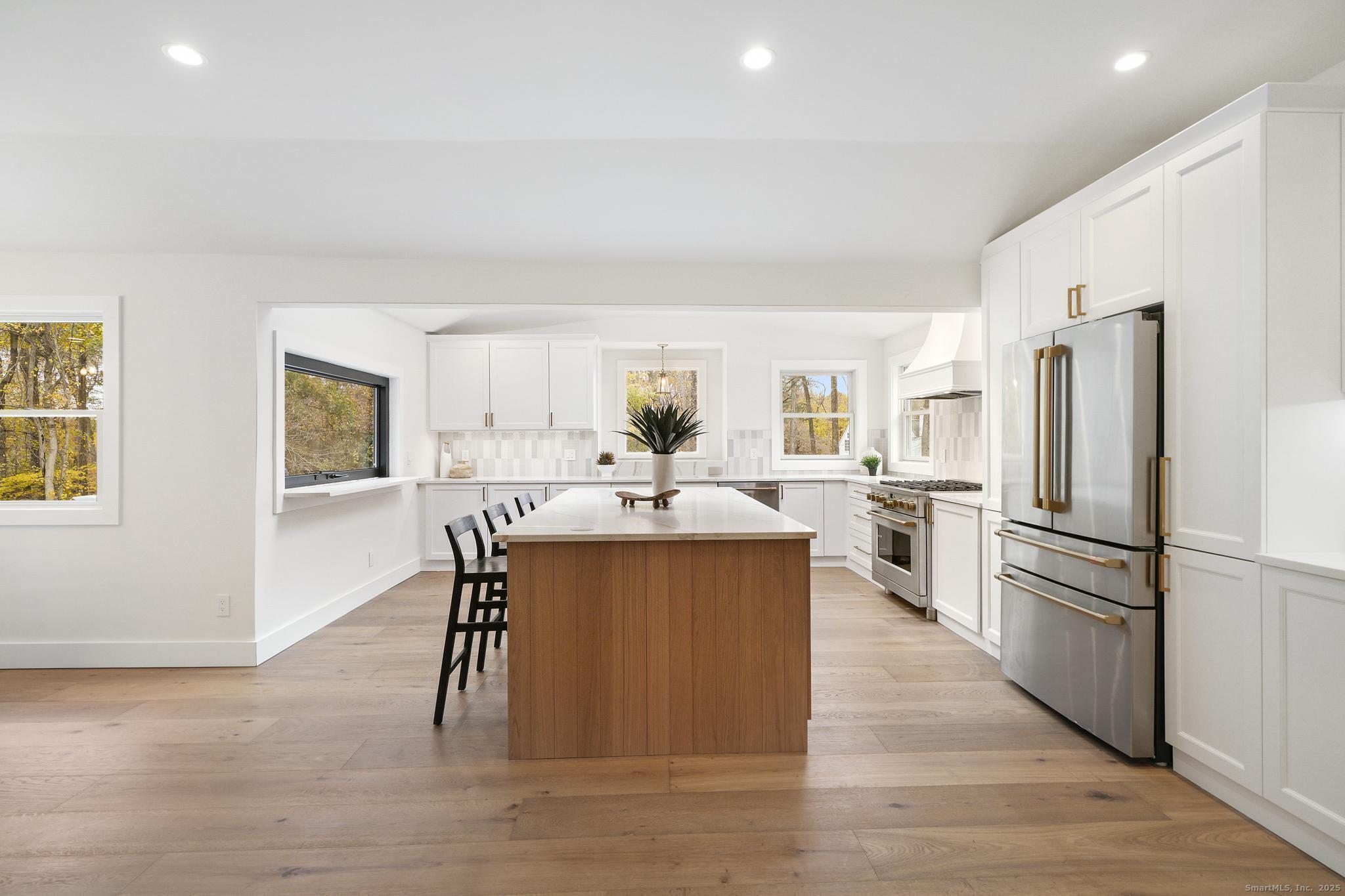 55 Liberty Street Wilton, CT 06897 - Photo 7 of 23 a kitchen with stainless steel appliances a refrigerator a stove a sink dishwasher and a dining table with wooden floor